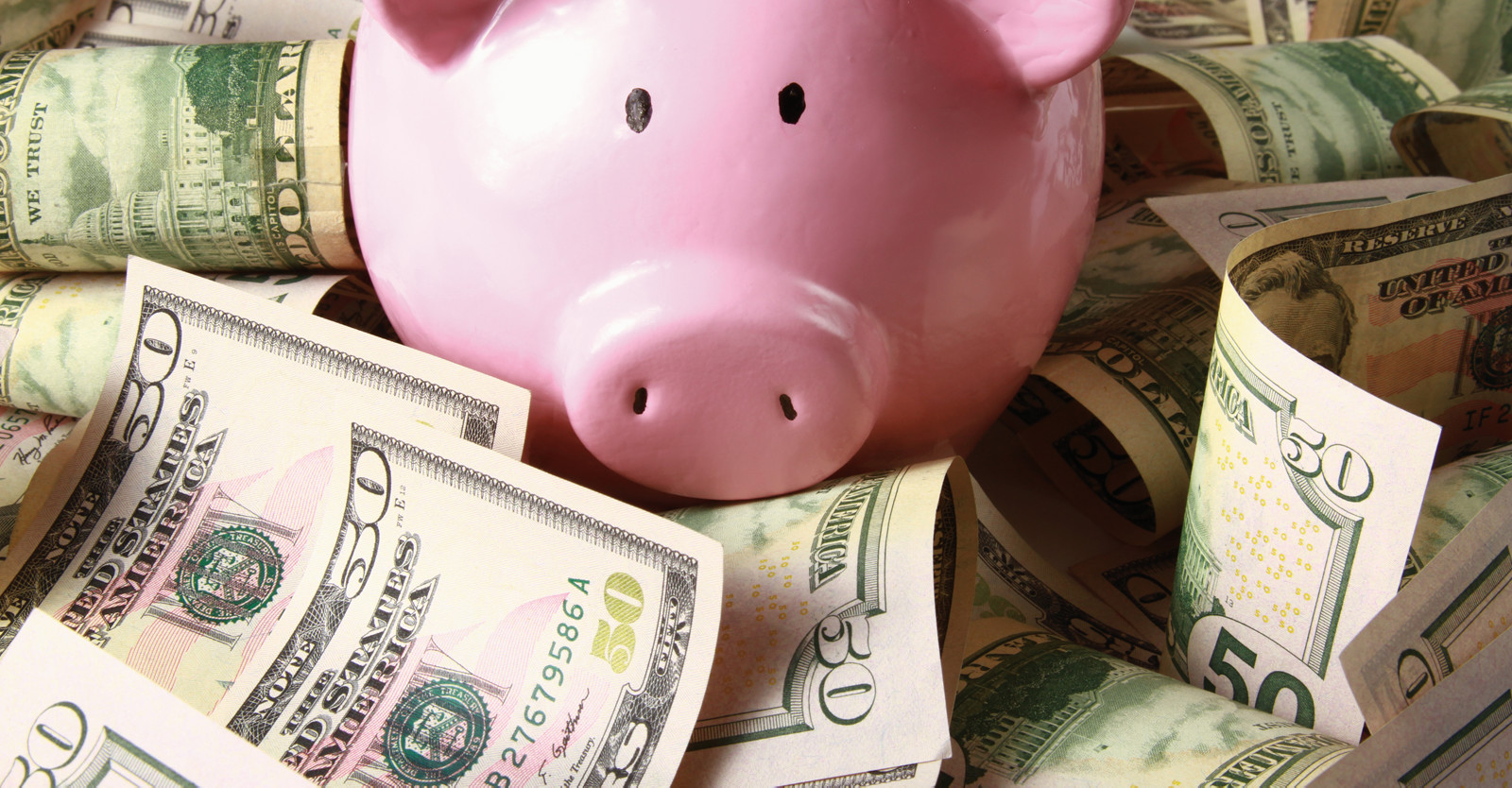 Pink piggy bank with money on a table