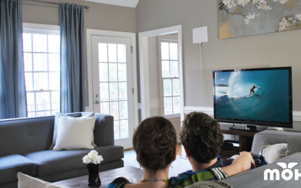 man and woman sitting on the couch watching tv mohu logo