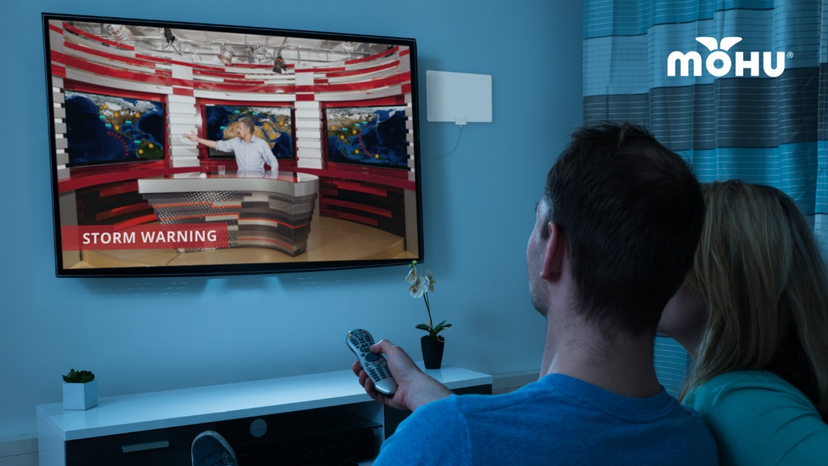 couple watching storm warnings in their livingroom